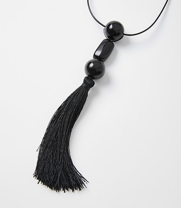 A black tassel hangs from a string of black beads against a plain white background.
