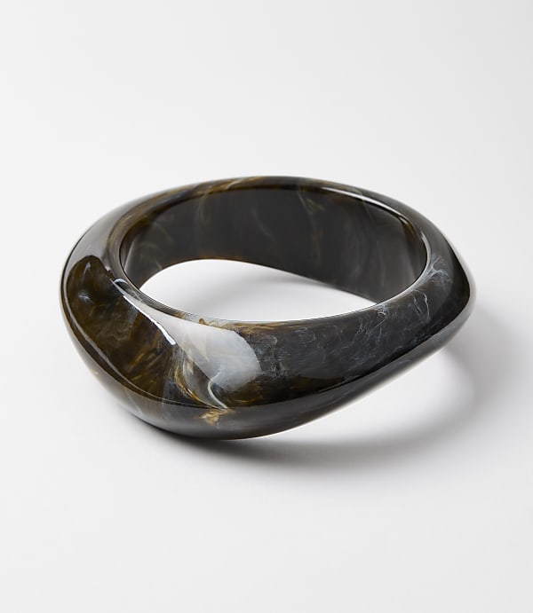 A swirling, dark brown and white marbled bangle rests on a plain white surface.
