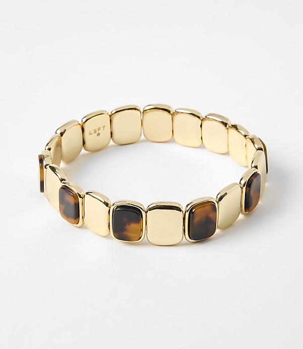 A gold bracelet with square tortoise shell accents rests on a plain white background.