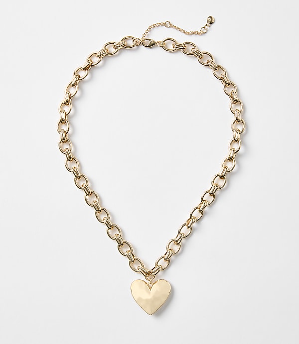 A gold heart pendant hangs from a chunky gold chain necklace against a plain white background.