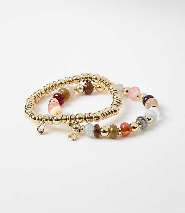 Two beaded bracelets, one with a gold chain and a diamond charm, rest on a plain white background.