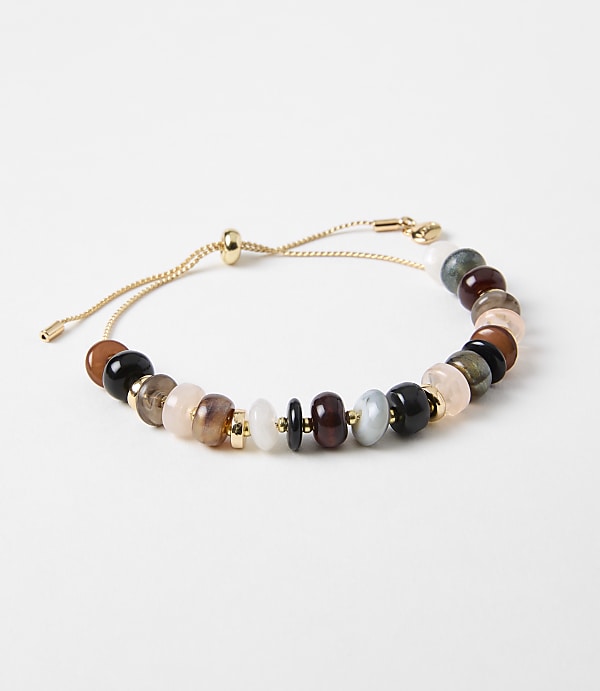A delicate gold chain bracelet with a variety of colorful gemstone beads is displayed against a plain white background.