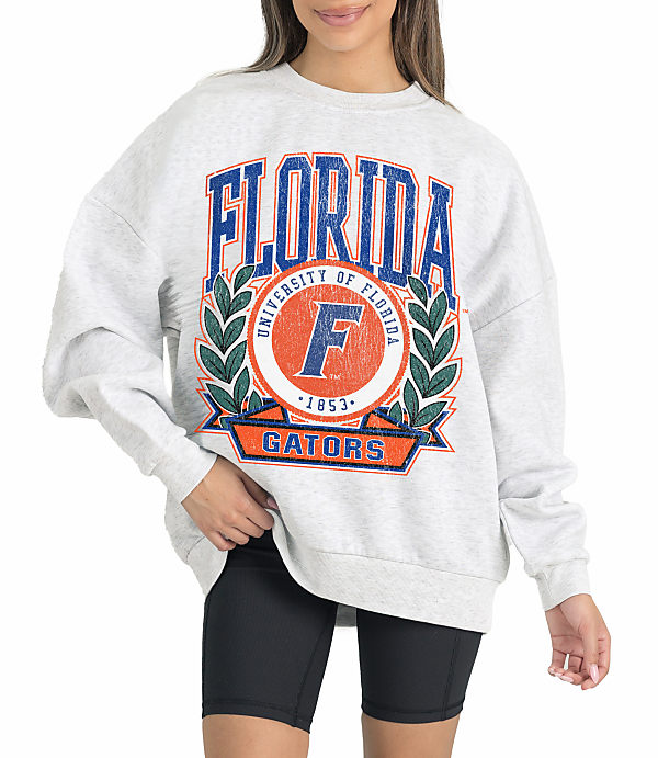 A woman in a grey sweatshirt with "Florida Gators" emblazoned on it stands against a white background.