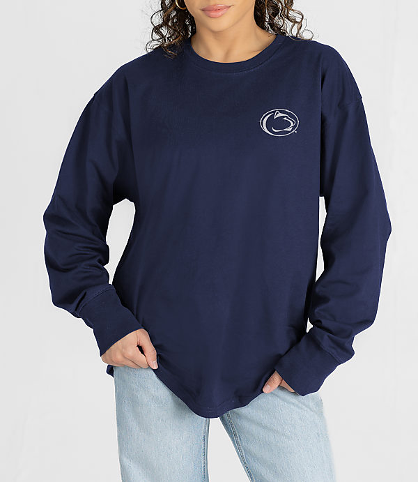 A woman in a navy long-sleeved shirt with a Penn State logo stands against a plain white background.