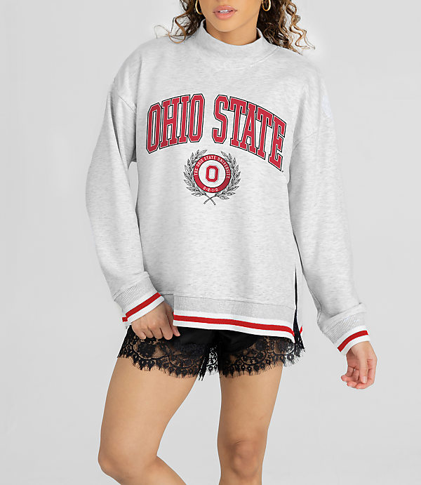 A woman in a grey Ohio State sweatshirt and black lace shorts stands against a white background.