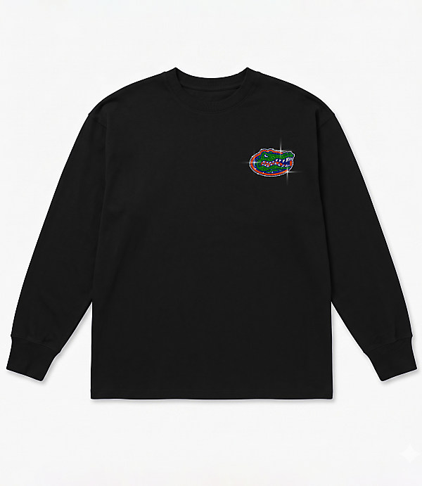 A black long-sleeved t-shirt with a glittery alligator logo on the left chest is laid flat against a white background.