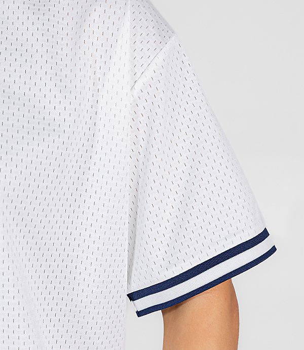 A close-up of a white mesh jersey with navy blue stripes on the sleeve is shown against a plain gray background.