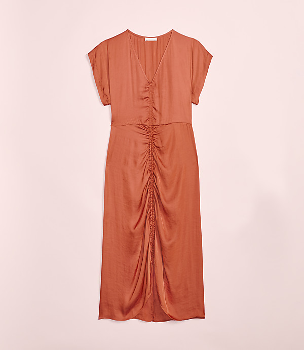 A rust-colored, ruched midi dress with short sleeves is laid flat against a soft pink background.
