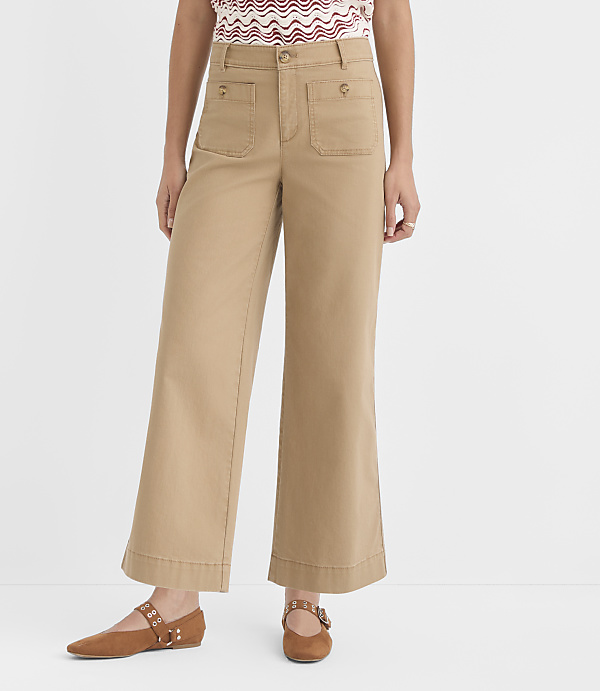 A person stands in tan wide-leg pants and brown flats against a plain white background.