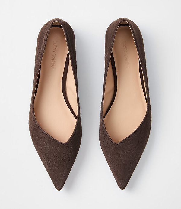 A pair of brown pointed-toe flats are laid out on a plain white background.