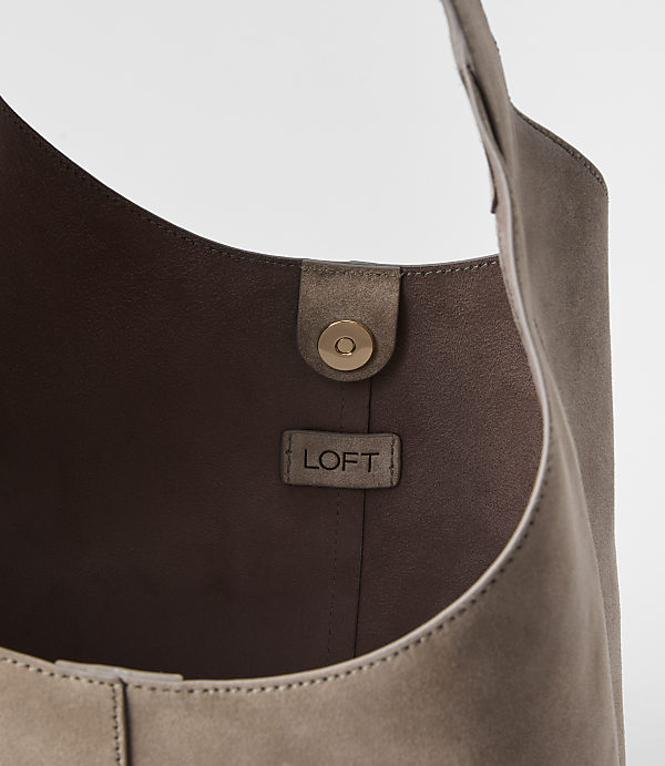 A taupe suede hobo bag with a gold snap closure and a LOFT logo tag is shown against a plain white background.