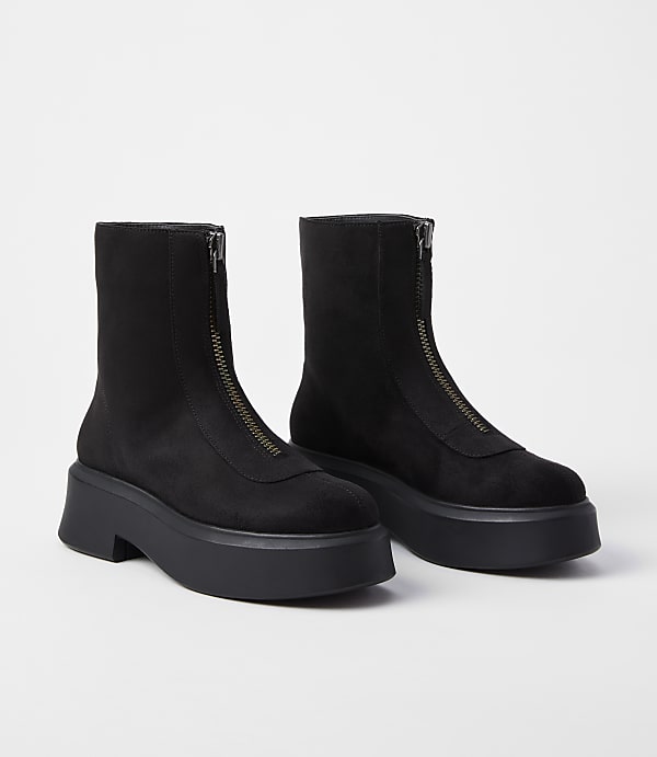 A pair of black, zip-front platform boots rests on a plain white background.