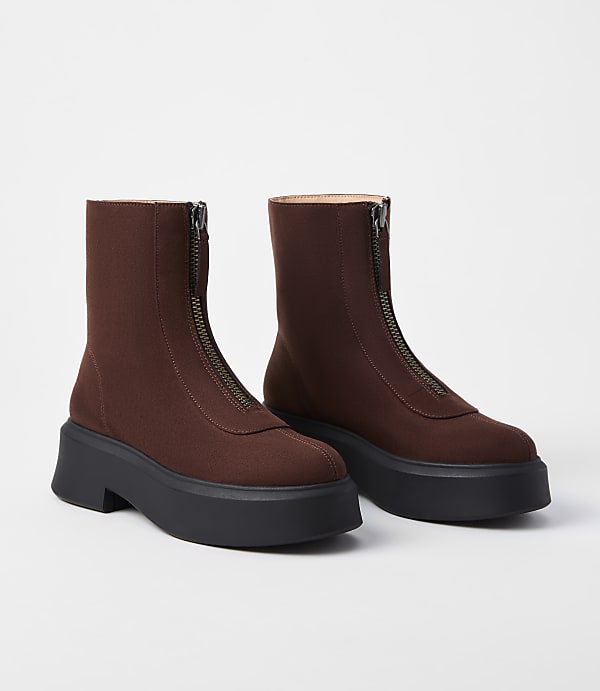 A pair of brown zip-up ankle boots with thick black platform soles are displayed against a plain white background.