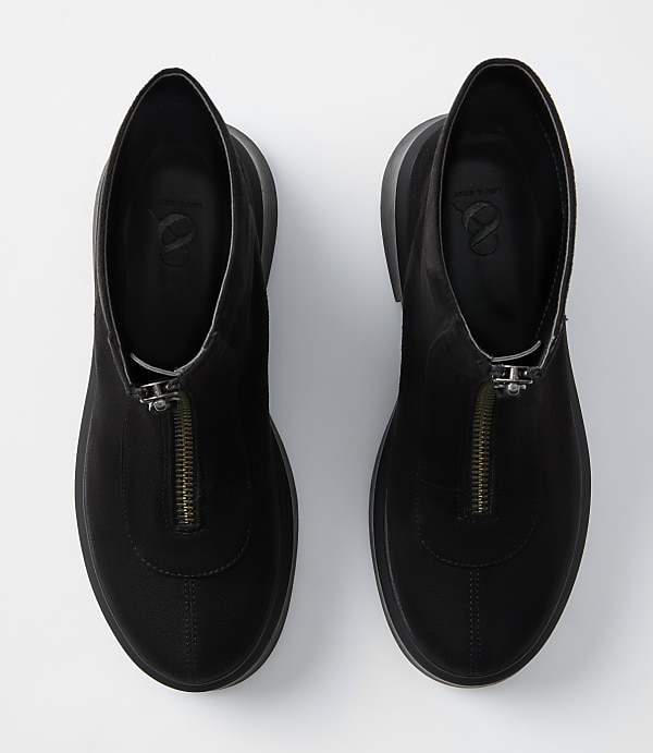 A pair of black zippered ankle boots with thick soles rests on a plain white background.