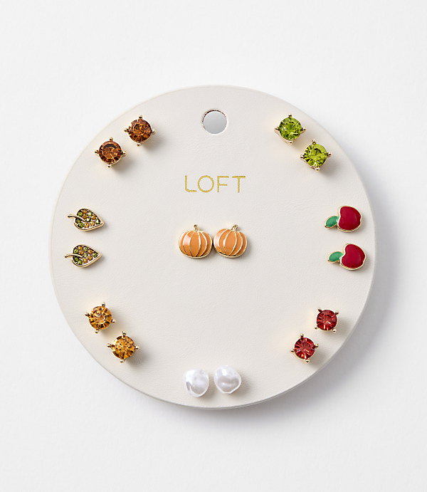 A circular white card displays an assortment of small, colorful stud earrings, including pumpkins, leaves, apples, and gemstones, against a plain white background.