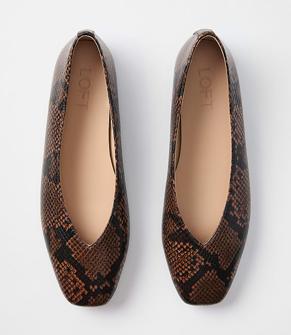 A pair of brown snakeskin print ballet flats with a V-shaped opening are laid flat against a plain white background.