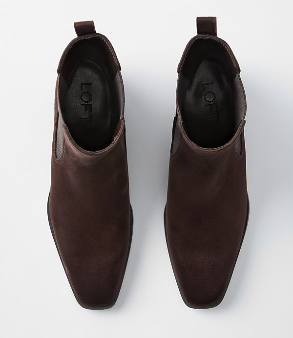 A pair of brown suede Chelsea boots with square toes are laid out on a plain white background.
