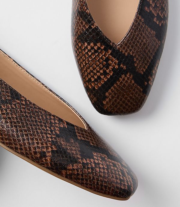 A pair of brown snakeskin pointed-toe flats rests on a plain white background.