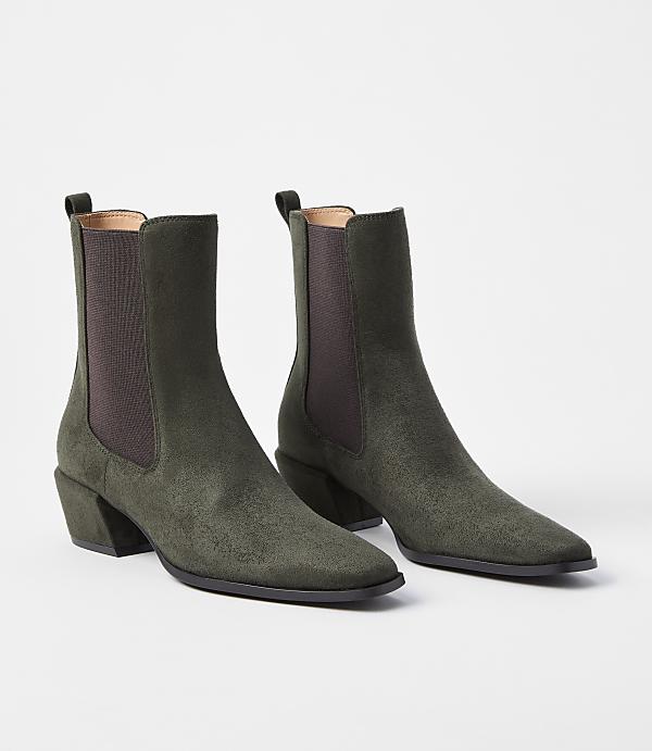 A pair of olive green suede Chelsea boots with block heels rests on a plain white background.