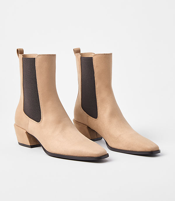 A pair of tan suede ankle boots with dark brown elastic side panels and block heels stand on a plain white background.
