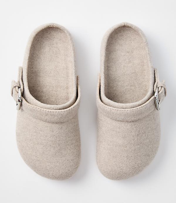 A pair of beige felt clogs with silver buckles are displayed against a plain white background.