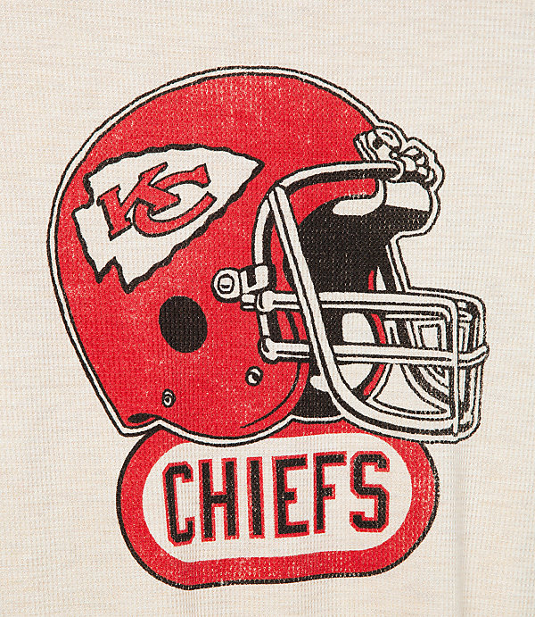 A distressed red Kansas City Chiefs helmet with the team logo is prominently displayed above the word "CHIEFS" in a vintage style, set against a plain, textured off-white background.
