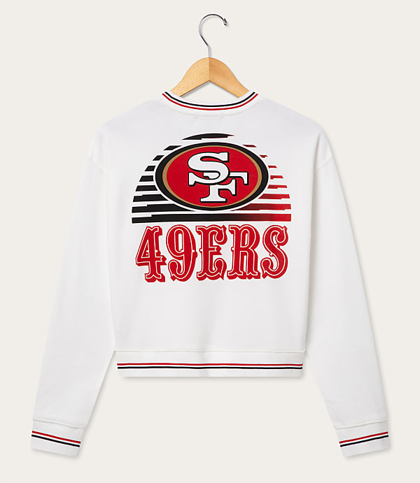 A white San Francisco 49ers sweatshirt with a graphic design on the back hangs on a wooden hanger against a plain white background.