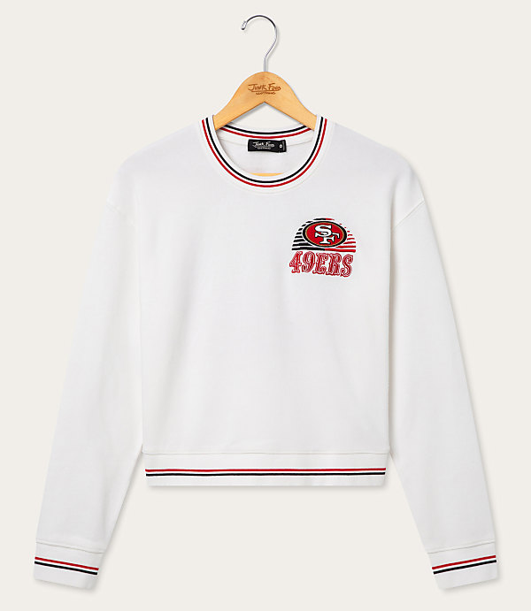 A white San Francisco 49ers sweatshirt with striped cuffs and neckline hangs on a wooden hanger against a plain white background.
