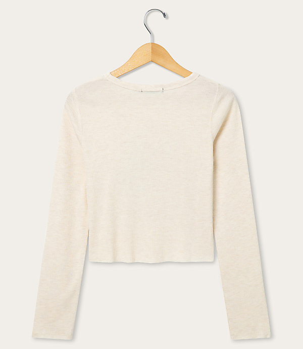 A cream-colored long-sleeved shirt hangs on a wooden hanger against a plain white background.