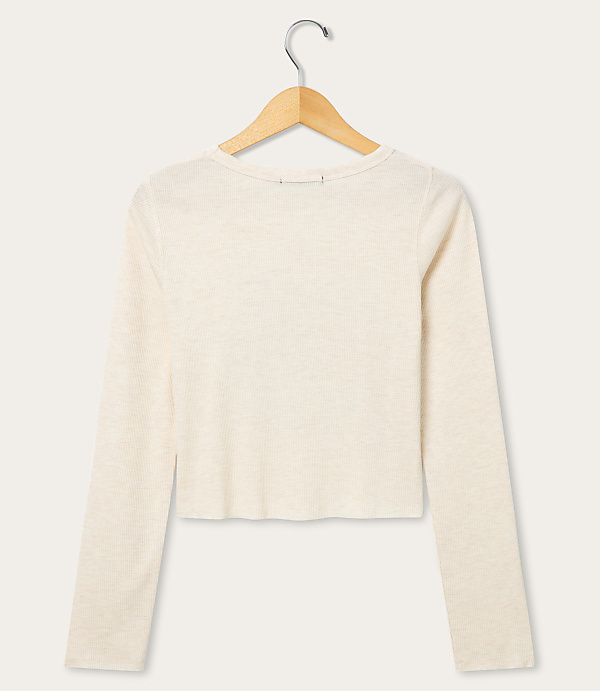 A cream-colored long-sleeved shirt hangs on a wooden hanger against a plain white background.