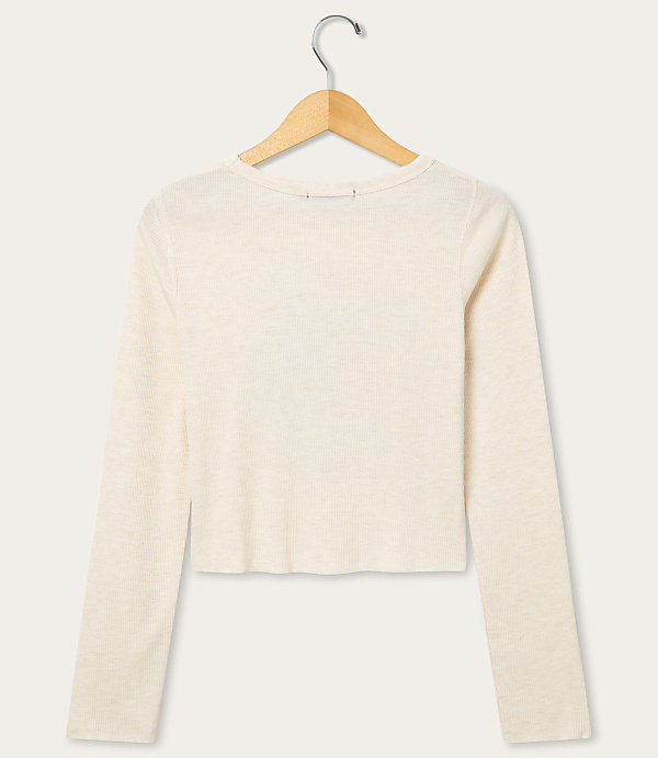 A cream-colored long-sleeved shirt hangs on a wooden hanger against a plain white background.