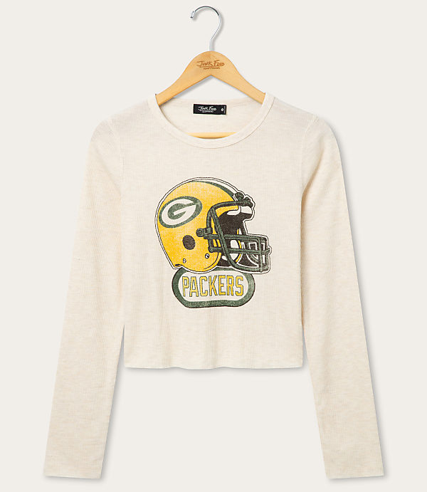 A cream-colored long-sleeved shirt with a vintage Green Bay Packers helmet graphic is displayed on a hanger against a plain white background.