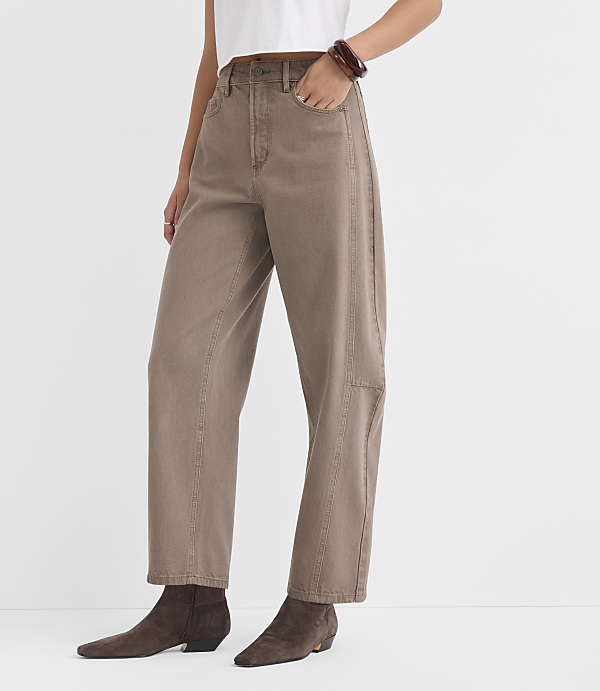A person wearing loose-fitting tan pants and dark brown ankle boots stands against a plain white background.