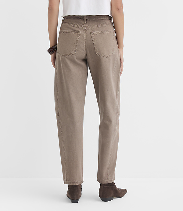 A person wearing brown jeans and boots stands against a plain white background.