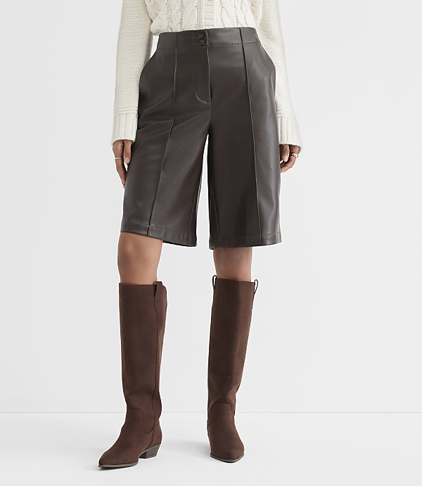 A person stands in brown leather culottes and knee-high brown boots against a plain white background.