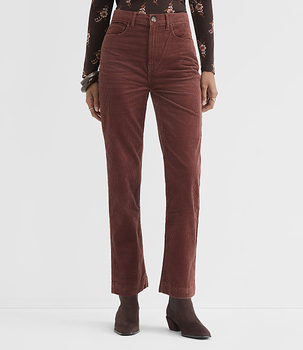 A person stands in rust-colored corduroy pants and a floral-patterned top against a plain white background.