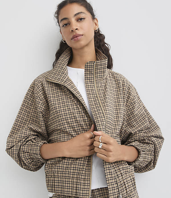 A woman in a plaid jacket stands against a plain white background.