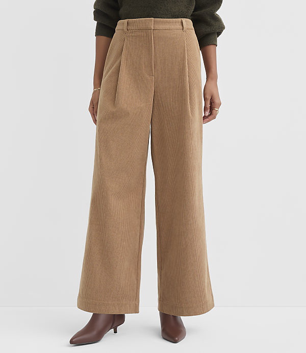 A person stands in wide-leg tan corduroy pants and brown heeled boots against a plain white background.