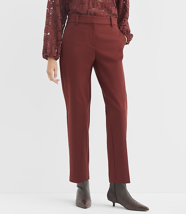 A person in rust-colored pants and a lace top stands against a plain white background.