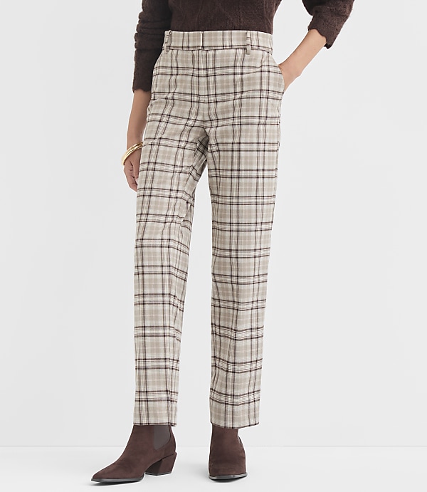 A person stands in the foreground wearing plaid pants and brown boots, against a plain white background.