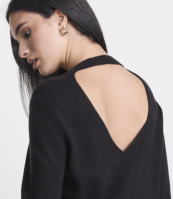 A woman in a black sweater with a deep V-back is shown from the shoulders up, with a plain white background.