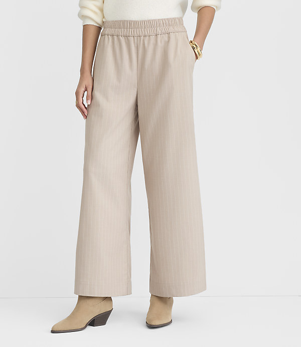 A person stands in beige pinstripe wide-leg pants and tan ankle boots against a plain white background.