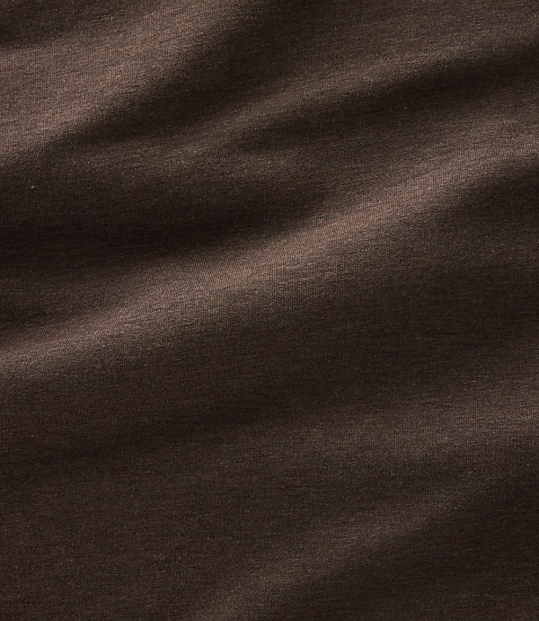 Dark brown fabric with soft folds and subtle highlights creates a textured background.