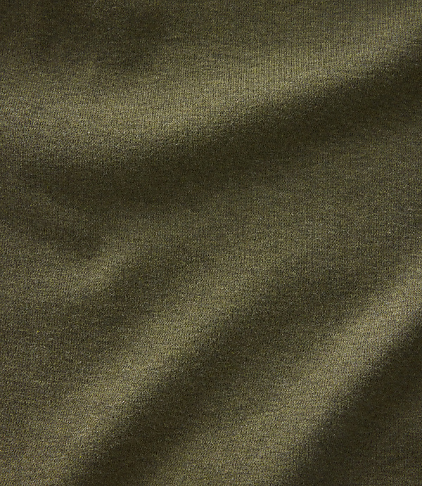 A close-up of olive green fabric with soft folds and subtle lighting creates a textured foreground against a plain, dark background.