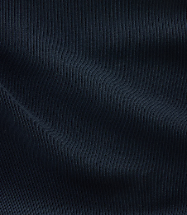 A dark blue, ribbed fabric with soft folds fills the frame, creating a textured and shadowed surface.