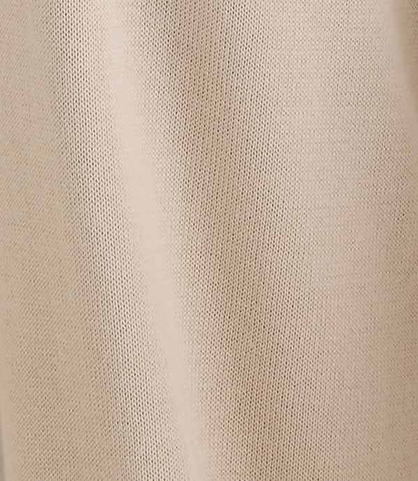 A close-up of a beige knitted fabric fills the frame, with subtle folds and shadows creating depth.
