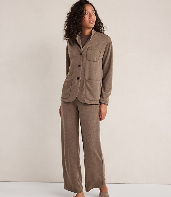 A woman in a brown loungewear set stands against a plain, light brown background.
