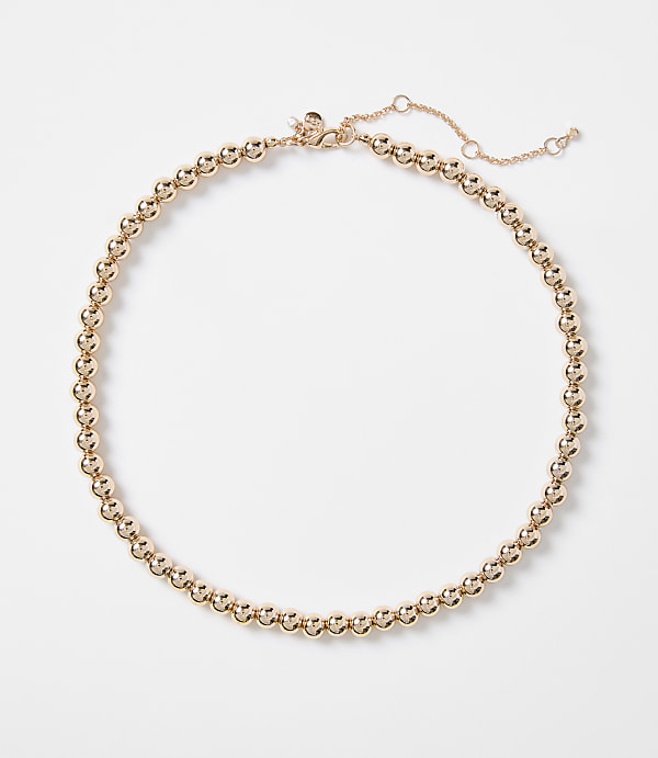 A rose gold beaded necklace with a delicate chain closure rests on a plain white background.