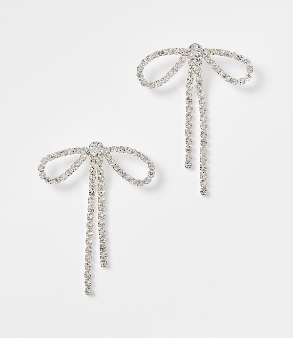 Two sparkling bow-shaped earrings with dangling chains are set against a plain white background.