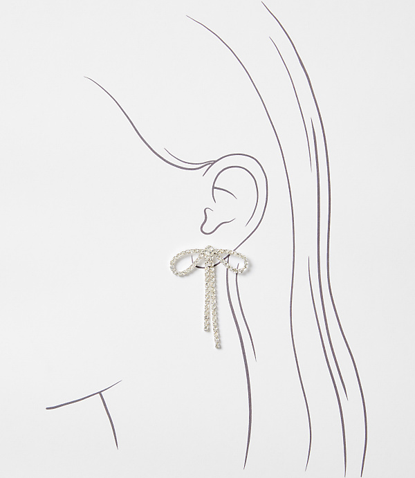 A sparkling bow earring with dangling chains adorns an illustrated ear against a plain white background.